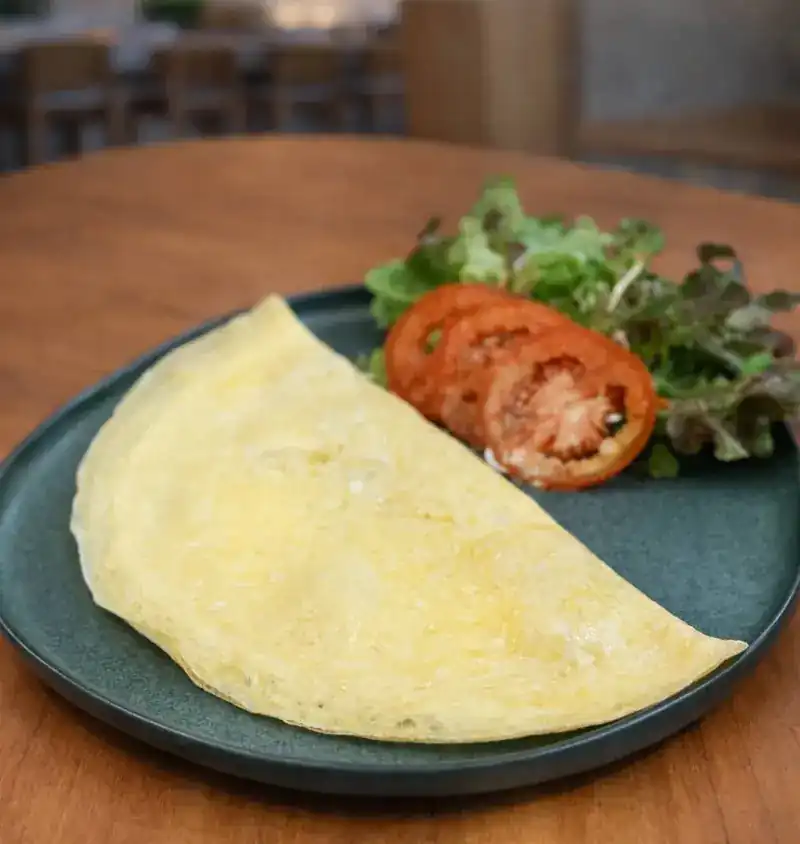 Folded cheddar omelet with sliced tomato and salad leaves