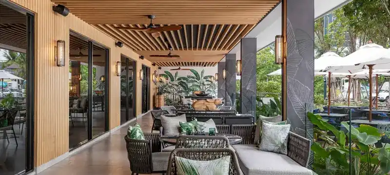 Covered terrace with a slatted timber ceiling, woven armchairs and tropical plants