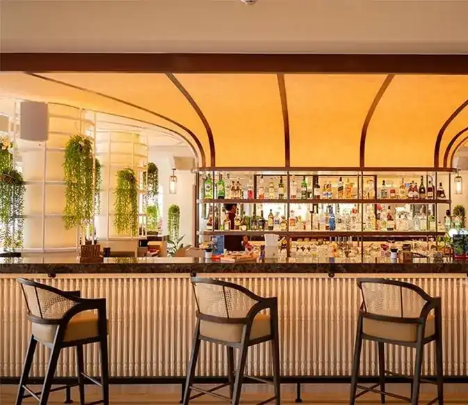 The bar under a warm curved ceiling, with rattan stools