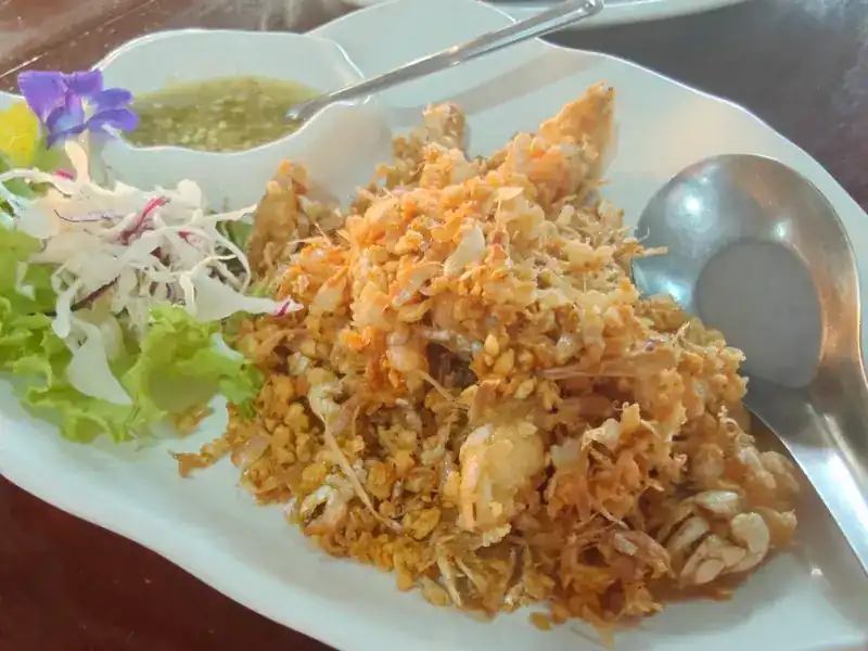 Seafood under a heap of crisp fried garlic, with green seafood sauce