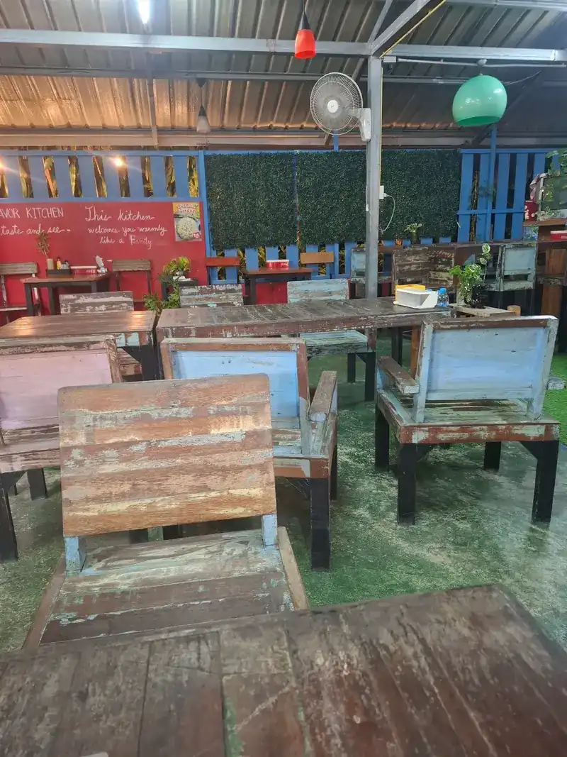Inside: weathered wooden tables, chairs painted blue and pink, and the red wall