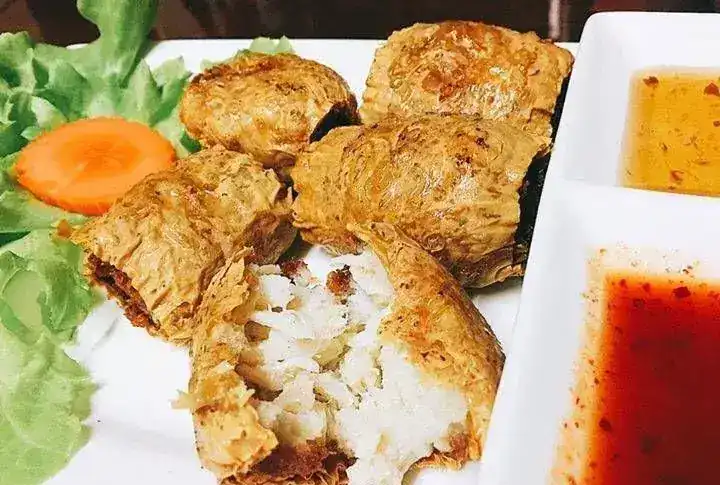 Golden fried crab rolls in tofu skin, one broken open, with two dipping sauces