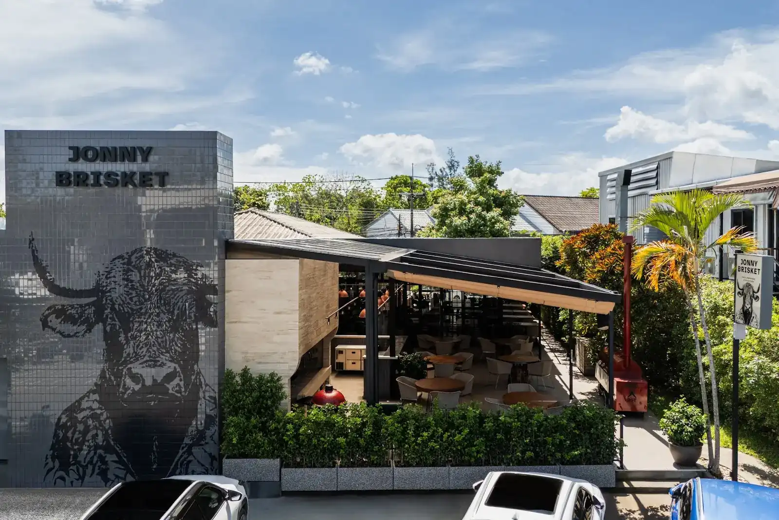 Jonny Brisket on Lagoon Road: a grey tiled wall with a bull's head and the open terrace beside it