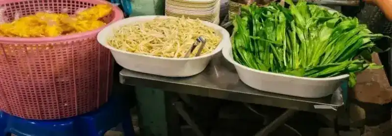 At the counter: a bowl of bean sprouts, a bowl of fresh greens and a pink basket.