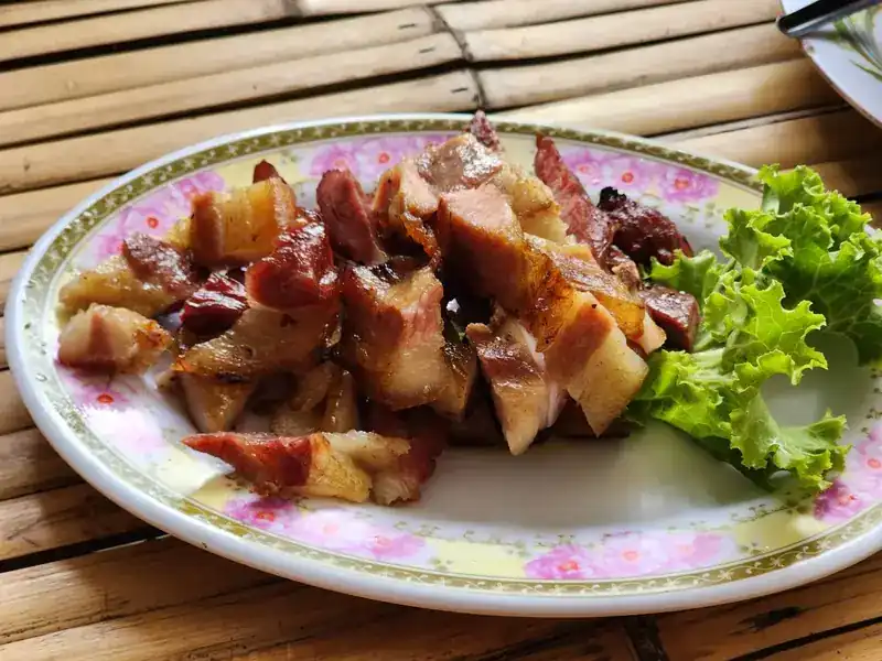 Pork with lettuce on a flowered plate, on a bamboo table