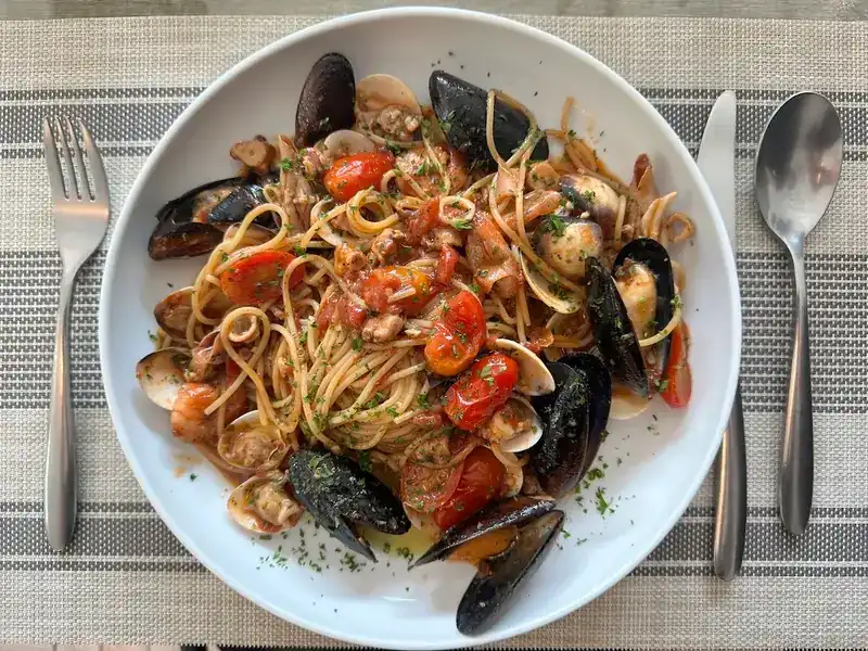 Spaghetti with mussels, clams and cherry tomatoes on a striped placemat