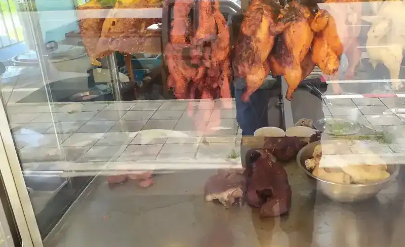 Crispy pork, red pork and roast birds hanging in the shop's glass case, more meats on the counter below