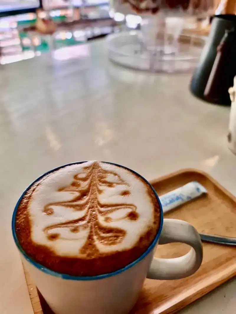 A coffee with latte art on a wooden tray