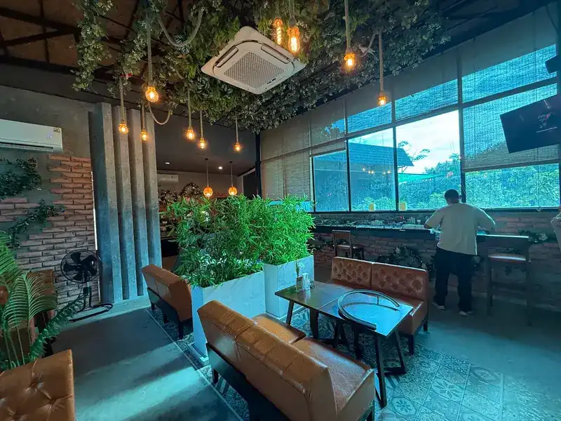 Leather sofas, bamboo planters and a window bar looking out at the trees. โซฟาหนัง กระถางไผ่ และบาร์ริมหน้าต่างที่มองออกไปเห็นต้นไม้