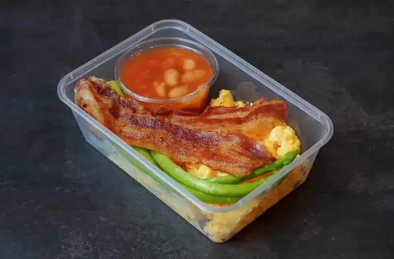 Scrambled egg with bacon, green vegetables and a pot of beans
