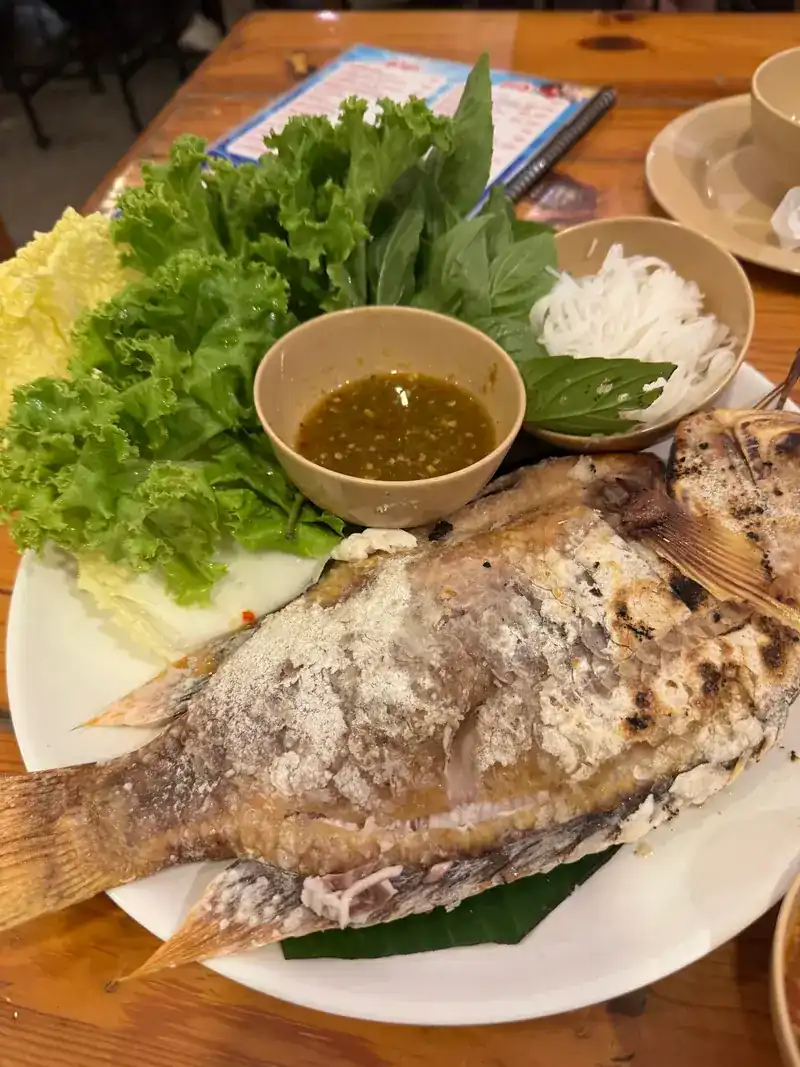 A whole fish grilled in salt, with lettuce, basil, rice noodles and dipping sauce