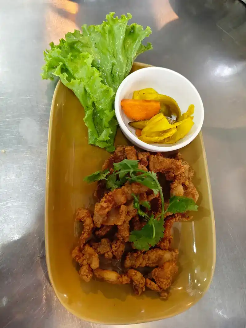 A crispy fried dish with coriander, lettuce and pickled vegetables