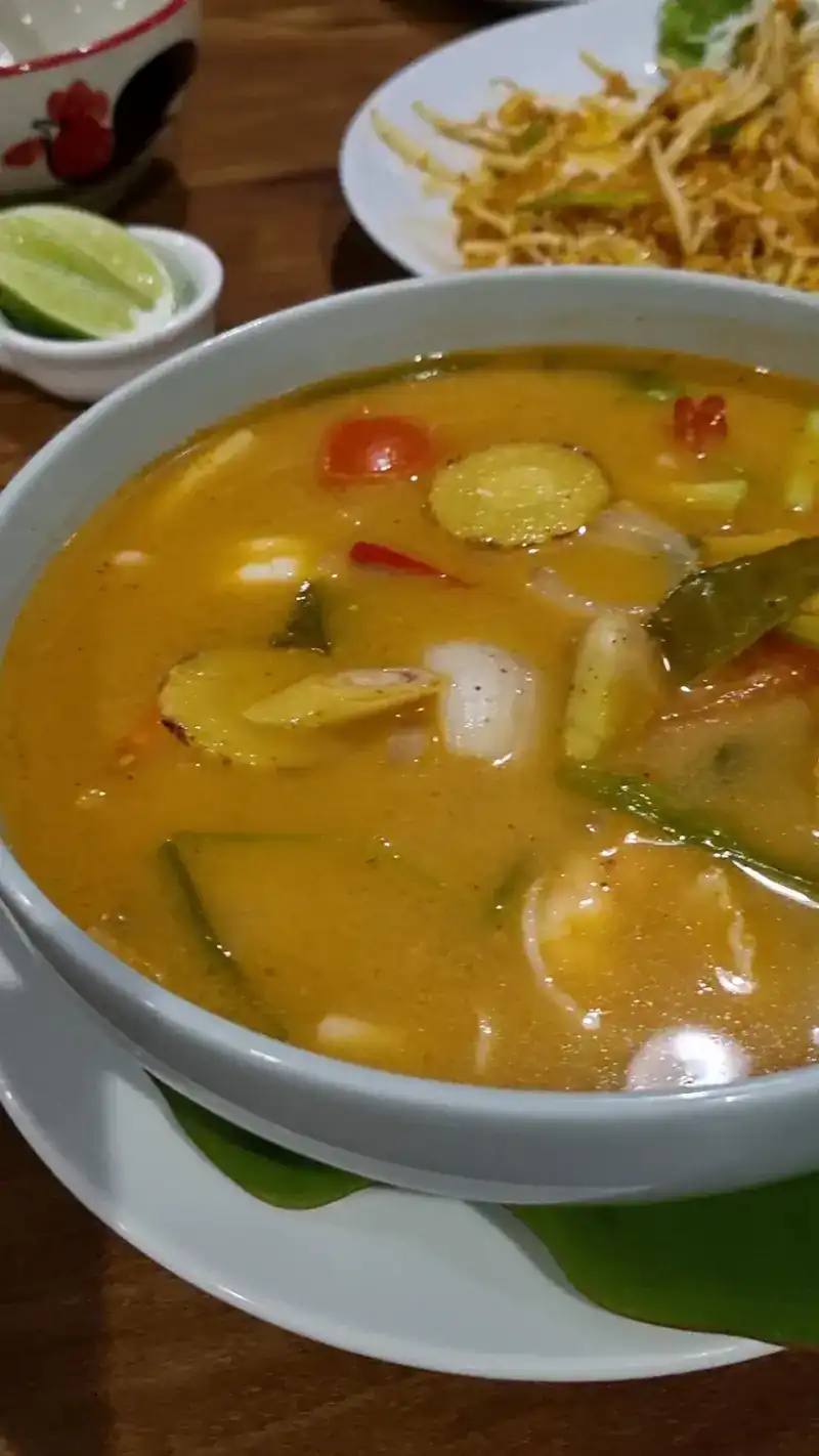 A bowl of tom yum with tomato and mushrooms