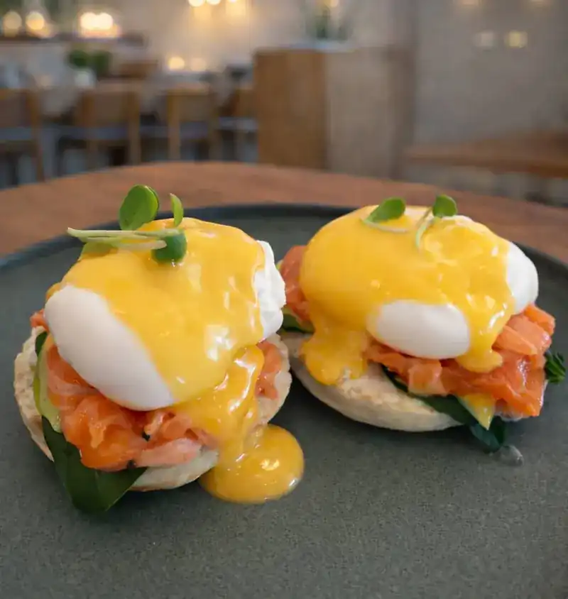 Eggs benedict with salmon, spinach and hollandaise running down the side