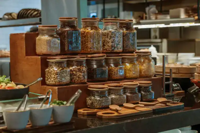 Jars of nuts, seeds and cereals on wooden steps at the breakfast buffet