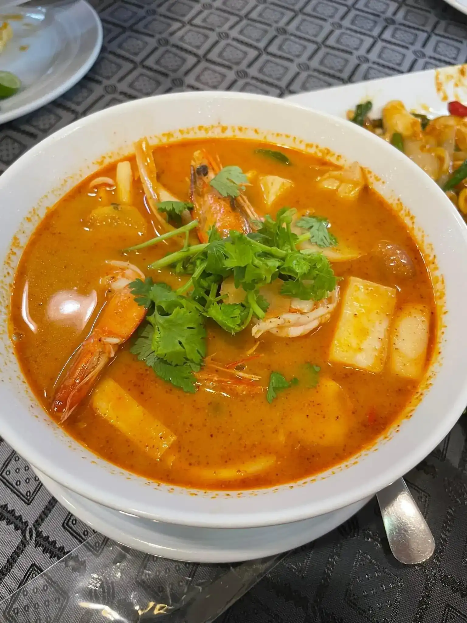 Tom yum with prawns and coriander in a white bowl