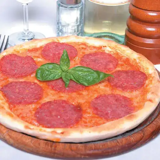 Pizza with Italian salami and basil on a wooden board