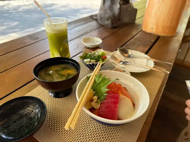 A sashimi rice bowl, miso soup and a tall green drink at the open front counter