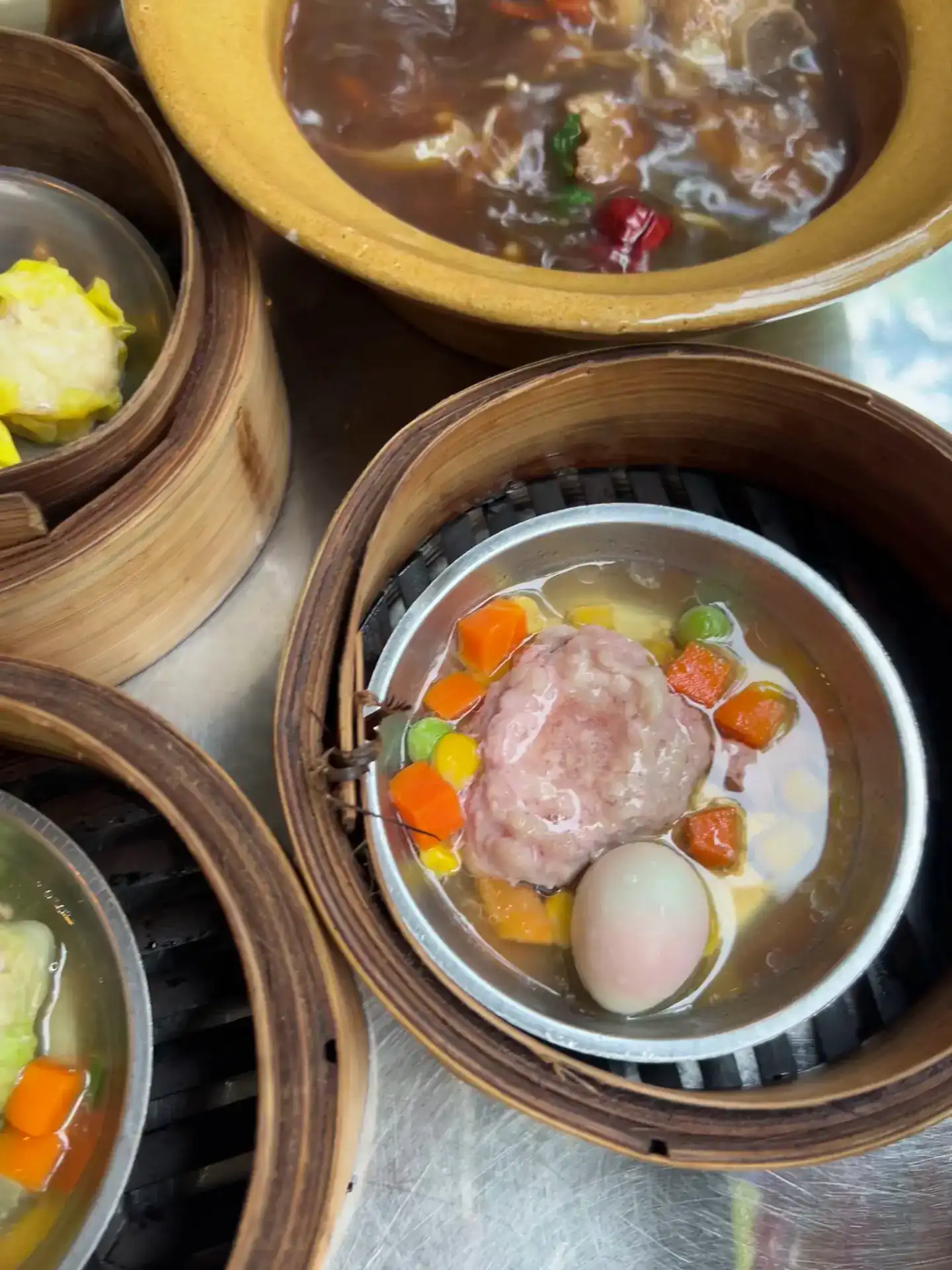 Bamboo steamers of dim sum, a cup of steamed pork with egg, and a bowl of dark herbal soup