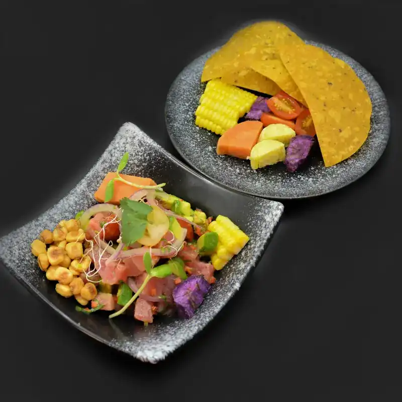 A salad of diced fish, corn and sweet potato beside a plate of crisp tortillas
