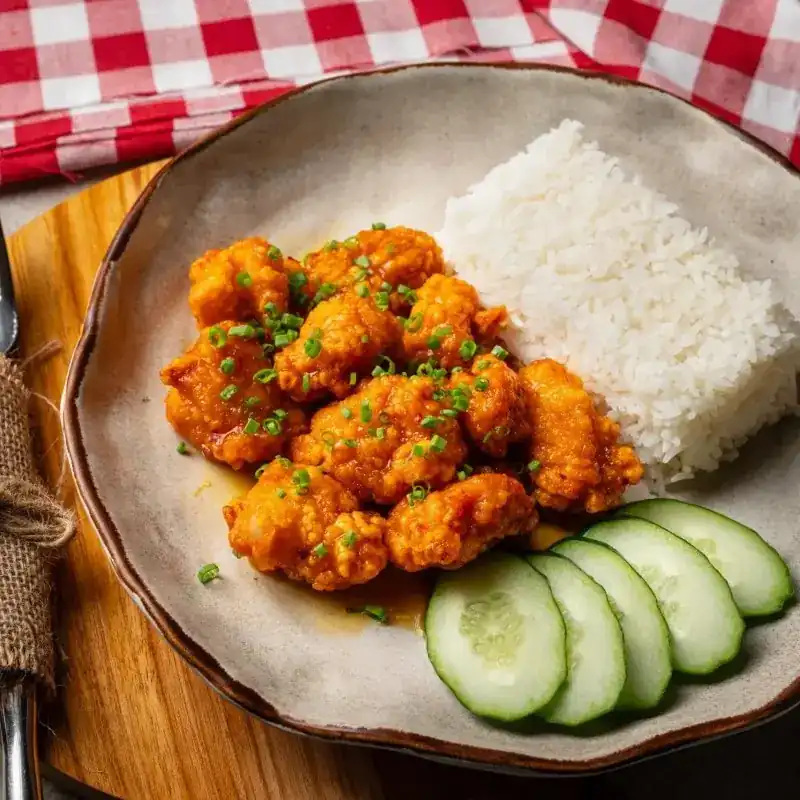Crispy chicken in an orange glaze with rice and cucumber