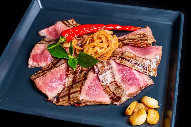 Sliced grilled beef, pink inside, with red chili, basil, crispy onions and roasted garlic