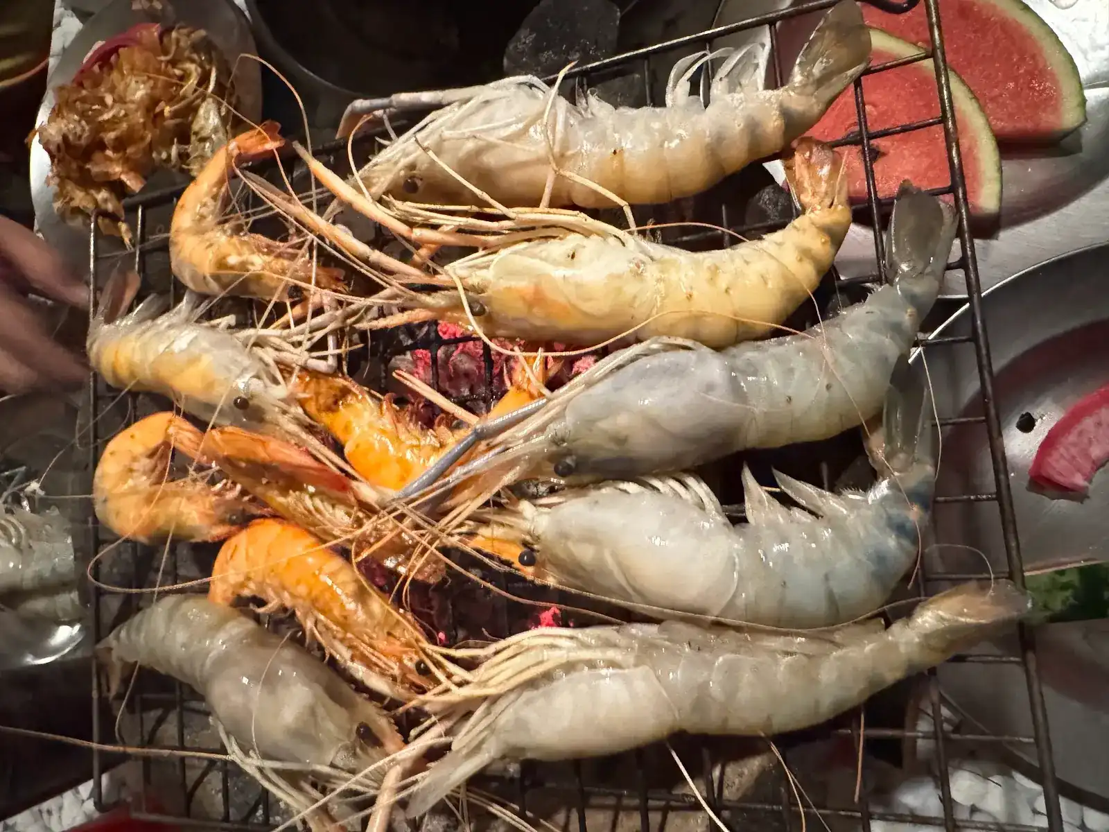 Big prawns on the charcoal grill, some still grey, some already orange