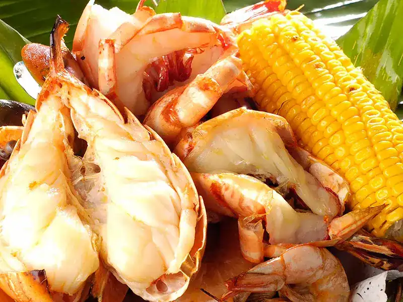 Grilled lobster, prawns and sweetcorn on banana leaf