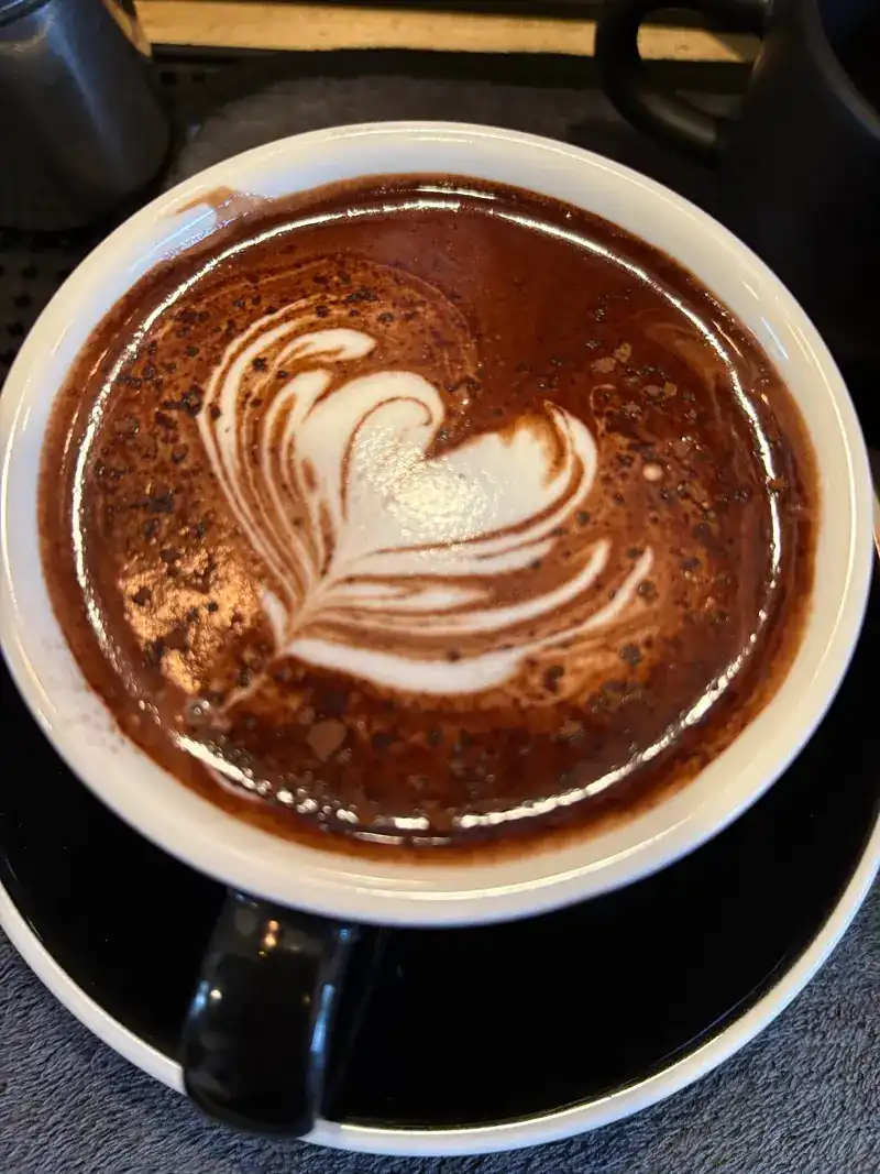 A hot drink with latte art in a white cup