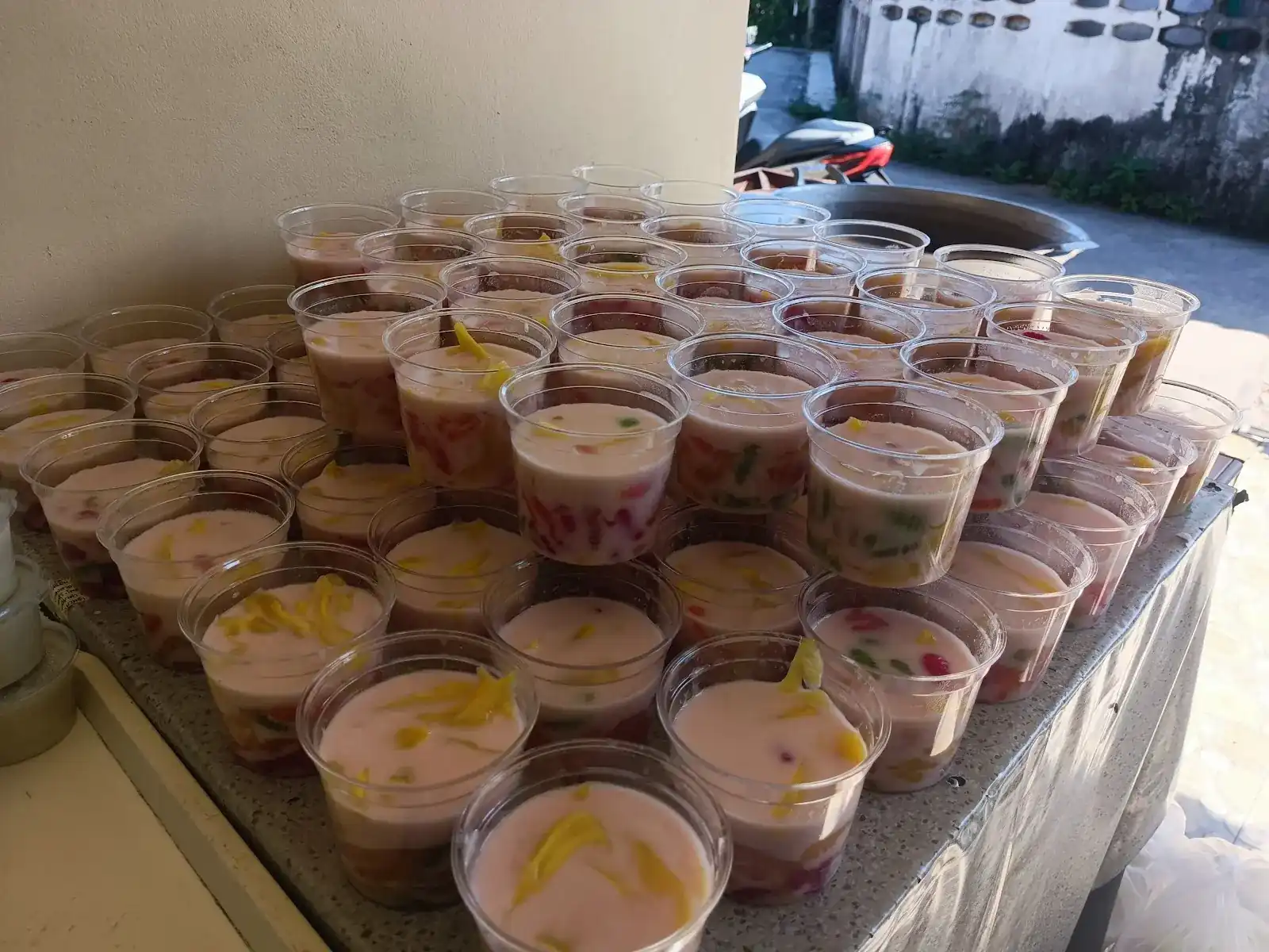 Dozens of pink dessert cups topped with yellow strips, set out on a table