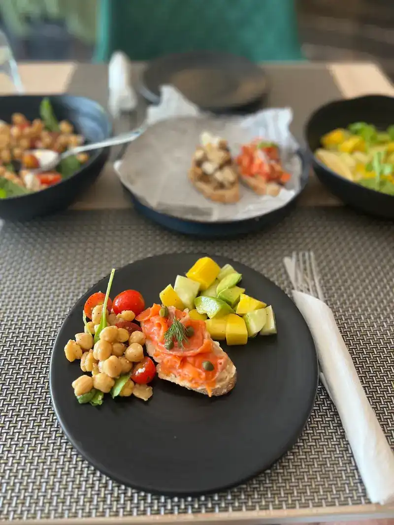 A plate of salmon bruschetta, chickpea salad, and mango with cucumber