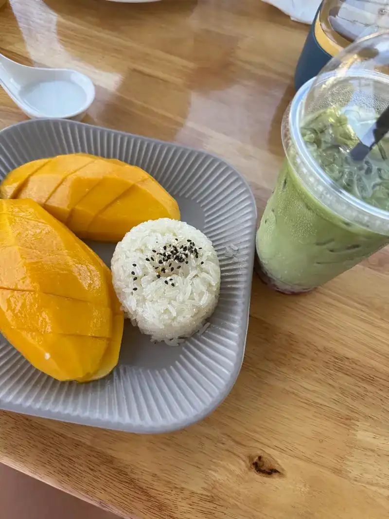 Mango sticky rice on a grey plate, with an iced green drink