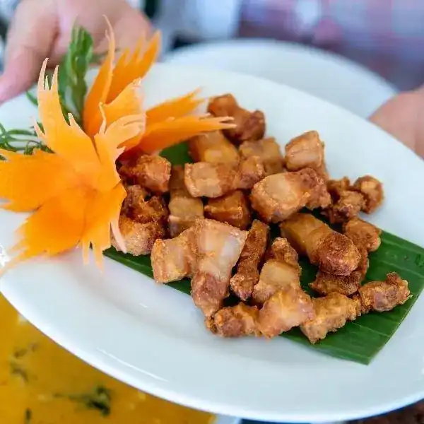 หมูทอดเกลือ: cubes of deep-fried pork on a banana leaf
