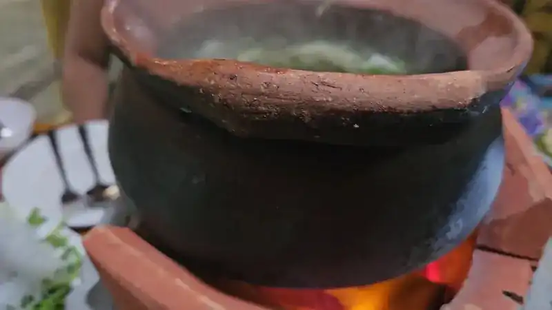 A clay pot over glowing charcoal