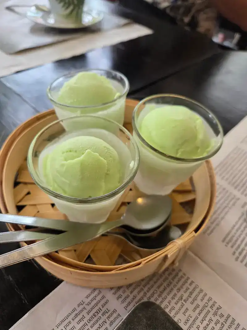 Three small glasses of pale green ice cream in a bamboo basket
