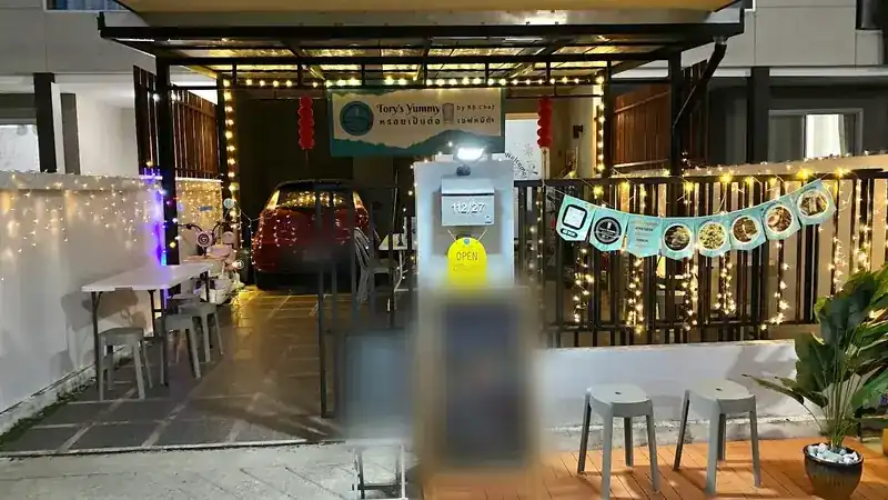 Tory's Yummy at night: the shop sign, fairy lights and stools at the gate of 112/27