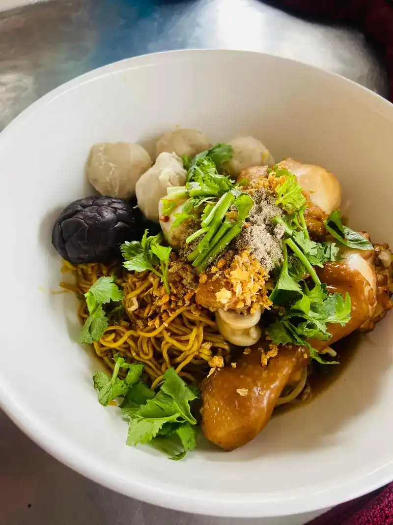 Egg noodles with braised chicken, meatballs, a shiitake mushroom and coriander