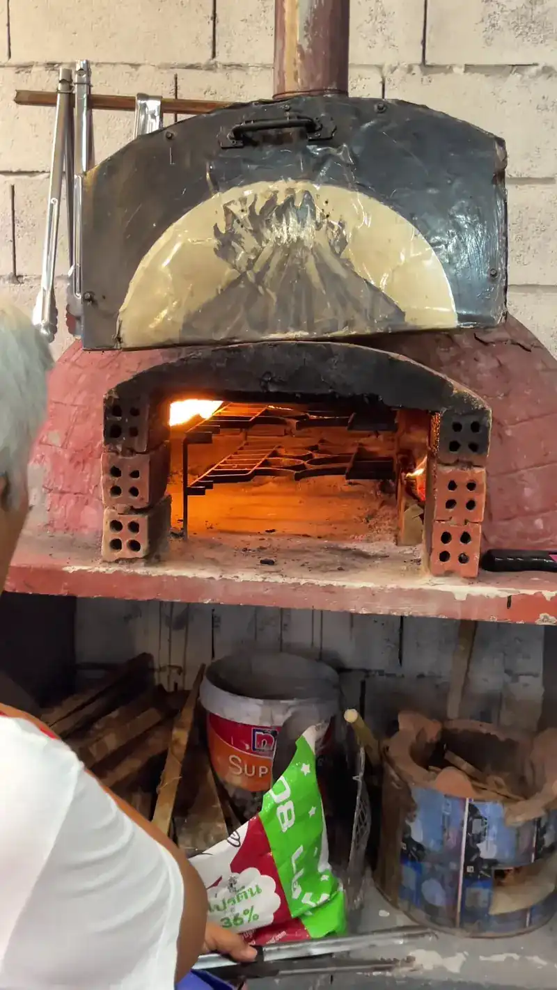 The dome oven with the fire burning inside, and wood stored on the shelf below