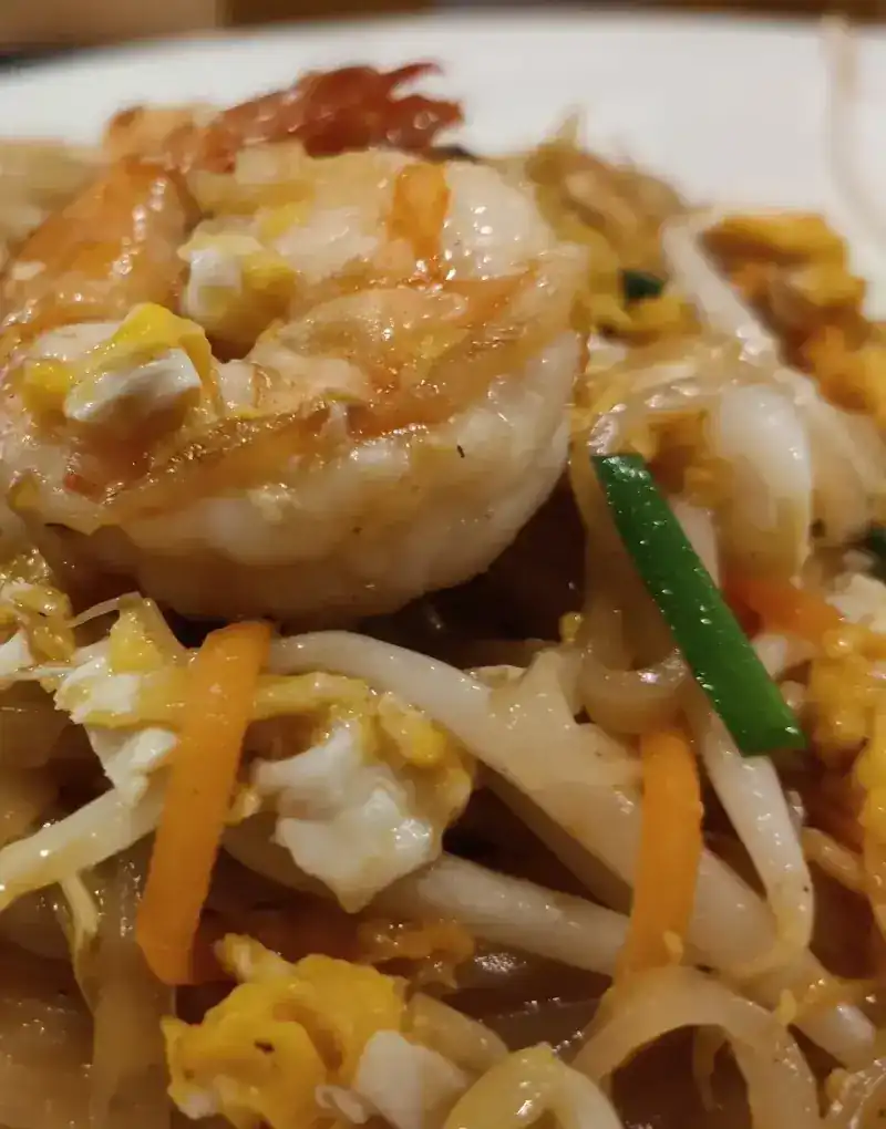 Stir-fried rice noodles with a large prawn, egg, carrot and bean sprouts