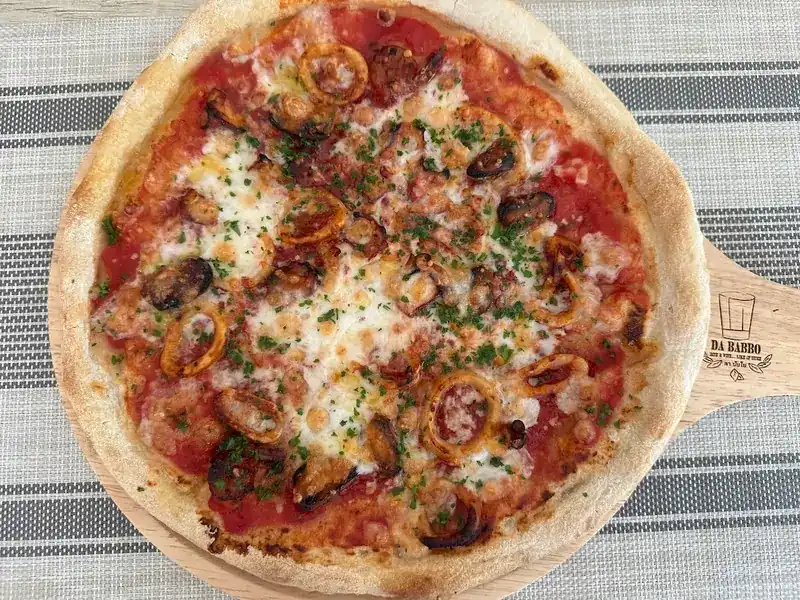 Seafood pizza on a wooden board marked Da Babbo