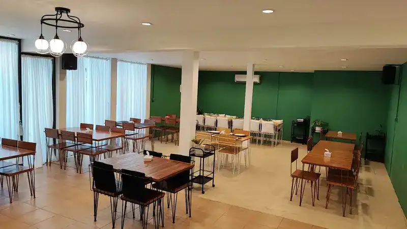 The dining room: green walls, wooden tables and globe lamps