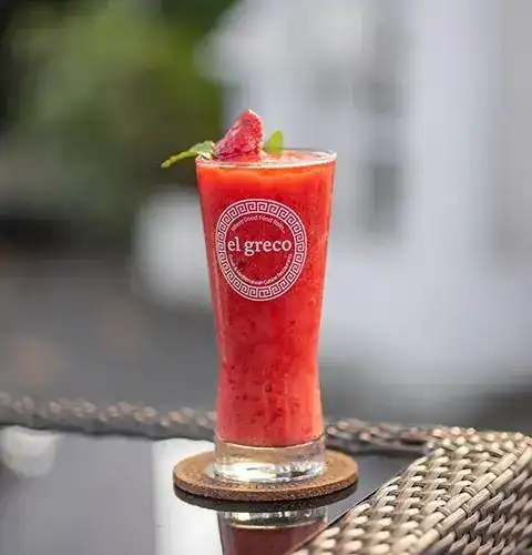 Red frozen drink with mint in a glass printed with the El Greco name