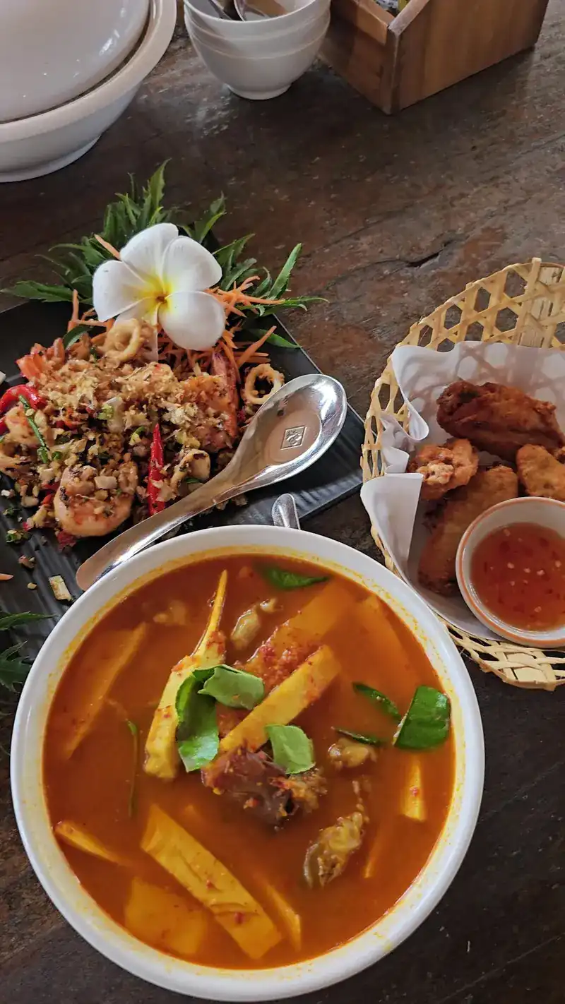 An orange curry with bamboo shoots, fried seafood with garlic and a basket of fried snacks