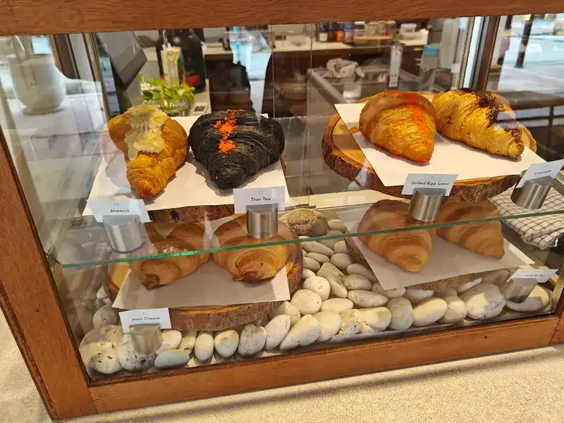 Croissants in the glass case on a bed of white pebbles, one of them black