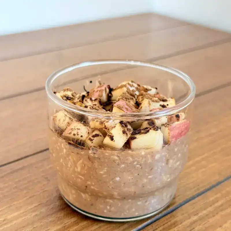 Overnight oats in a glass topped with diced apple and cinnamon