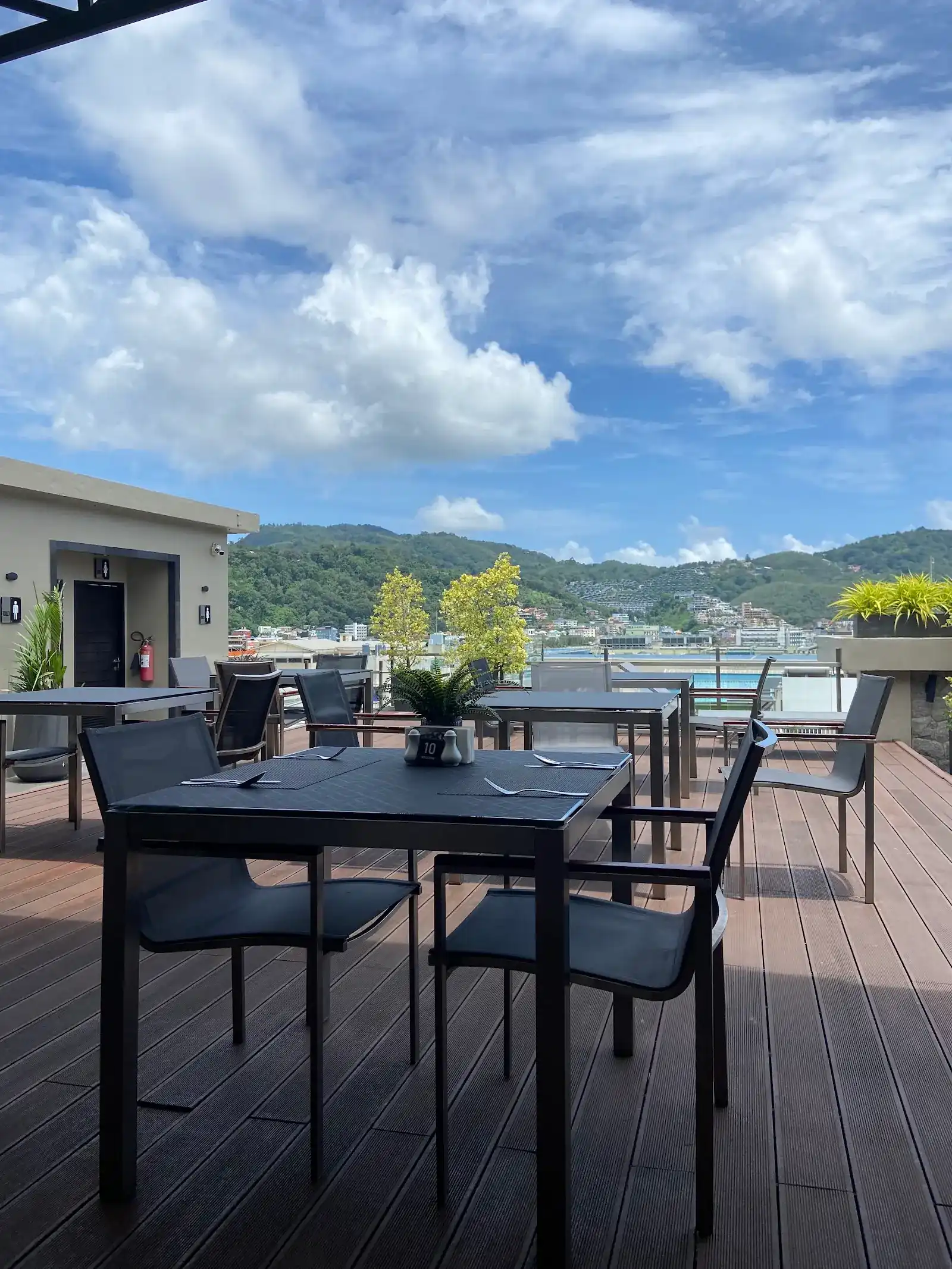 Tables set on Pasha's timber roof deck, with the green hills of Patong behind