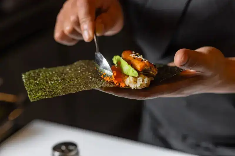 Eel, avocado and shrimp roe being spooned onto nori
