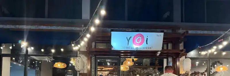 The Yoi sign with its pink circle above the entrance at night / ป้ายร้าน Yoi ที่มีวงกลมสีชมพู เหนือทางเข้าร้านยามค่ำ