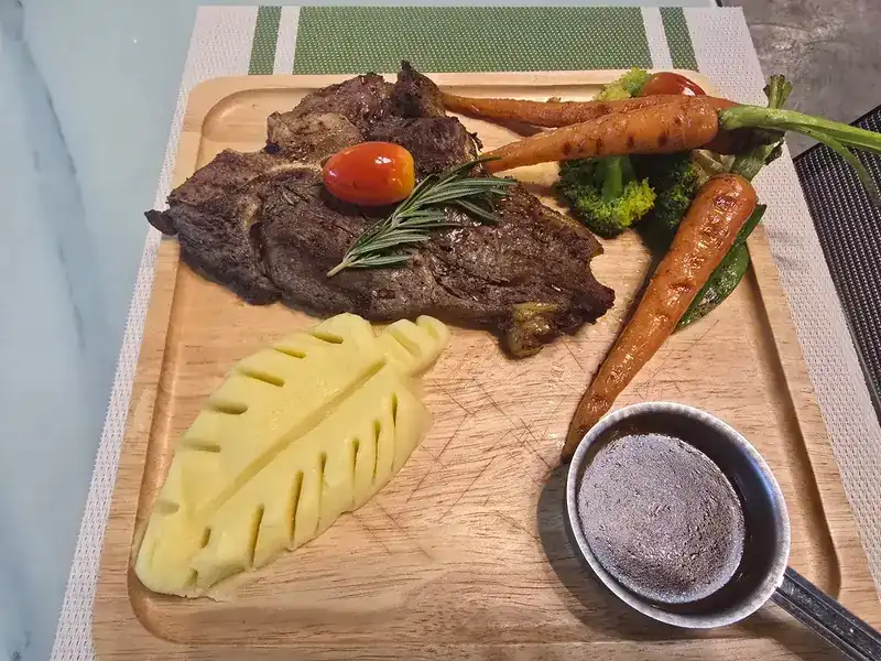 Grilled steak on a wooden board with mashed potato and roasted carrots