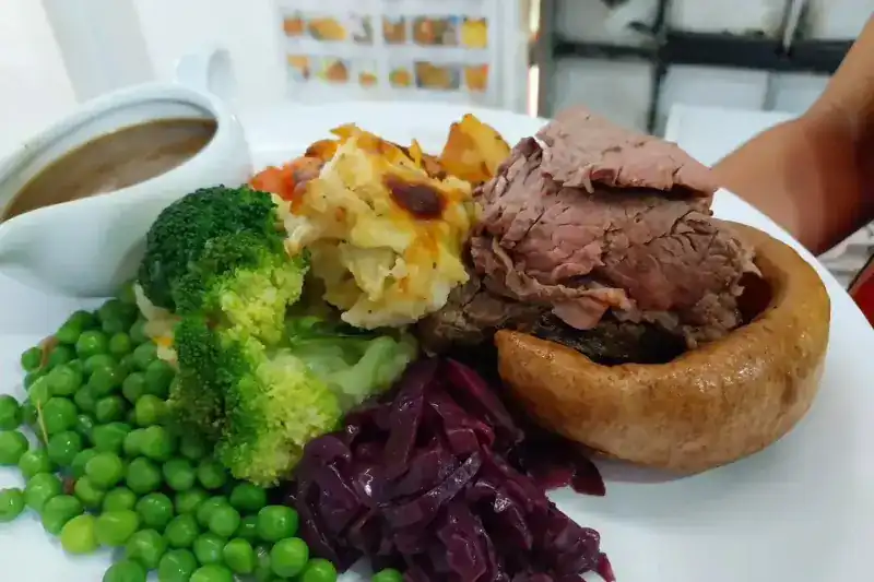 Roast beef in a Yorkshire pudding with peas, broccoli, red cabbage, cauliflower cheese and a jug of gravy